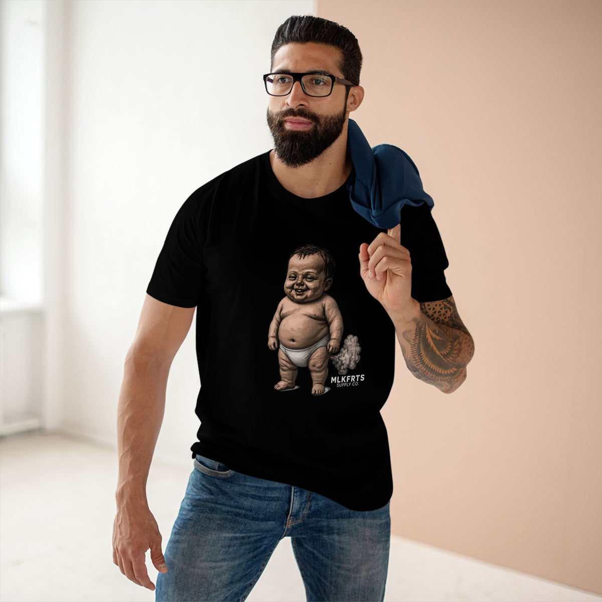 Man wearing the black MLKFRTS Lil' Stinker Tee, smug diaper baby with gas cloud on the front