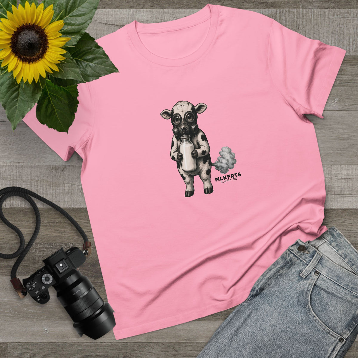 Bubblegum women's tee with the Calf of Concern on the front, flat lay with a sunflower, camera and jeans
