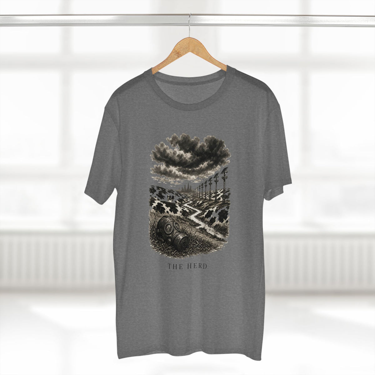 The Hills Have Cams Tee in heather grey on a hanger, front: etched surveillance hills with a gas mask in the grass, THE HERD.