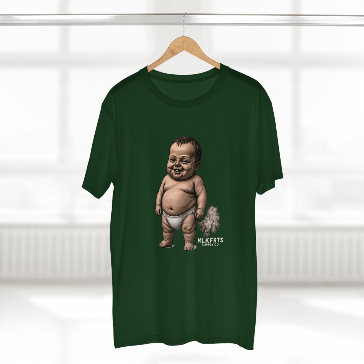Forest green MLKFRTS Lil' Stinker Tee on a hanger, smug diaper baby with gas cloud and milk puddles on the front