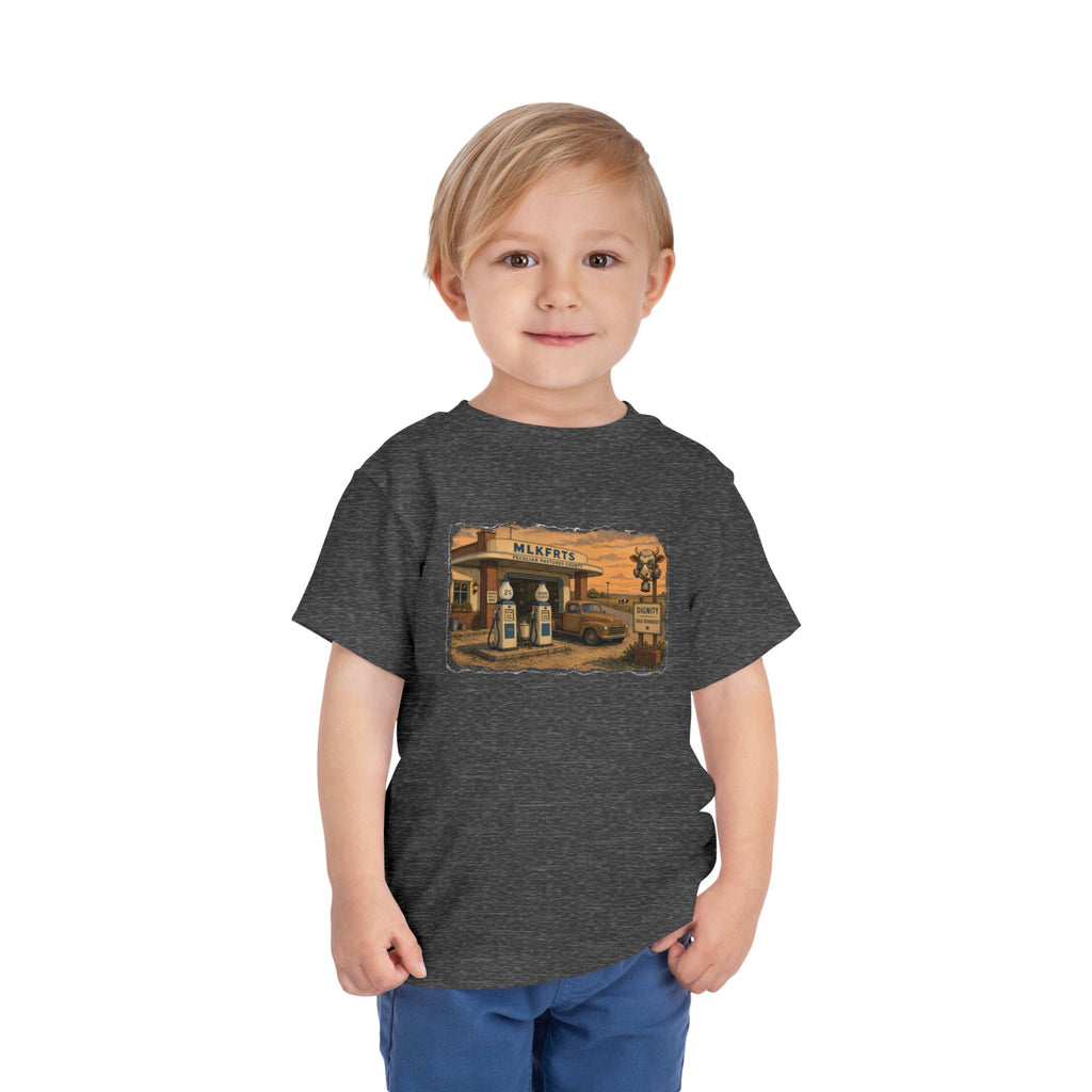 Toddler wearing the Peculiar Gas Station Toddler Tee in Dark Heather Grey, gas station scene on the front