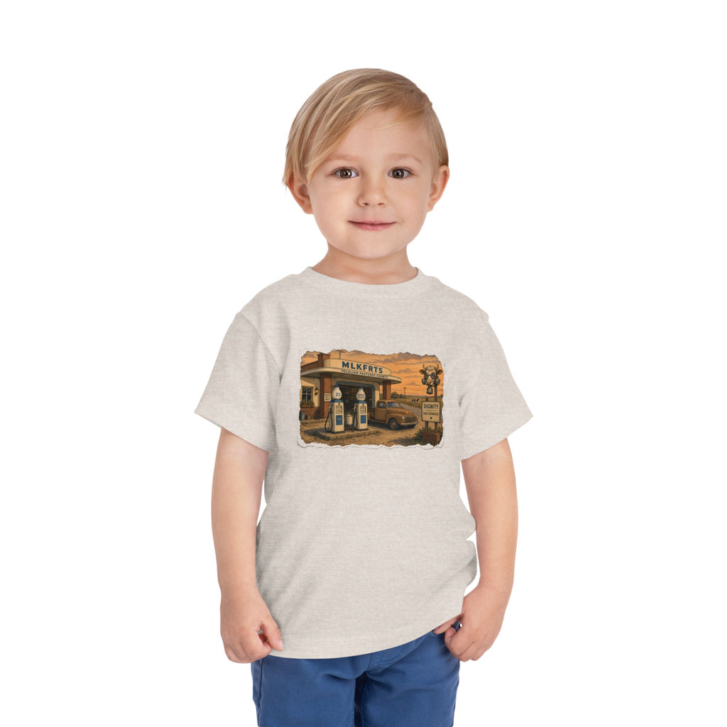 Toddler wearing the Peculiar Gas Station Toddler Tee in Heather Dust, gas station scene on the front