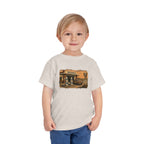 Toddler wearing the Peculiar Gas Station Toddler Tee in Heather Dust, gas station scene on the front