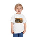 Toddler wearing the Peculiar Gas Station Toddler Tee in White, gas station scene on the front
