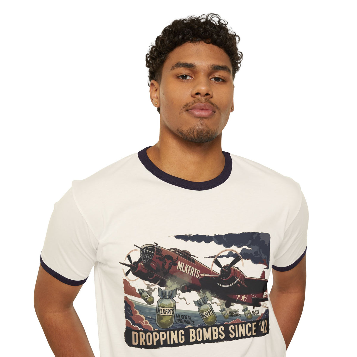 Model wearing the Natural/Midnight Navy ringer tee with a "Dropping Bombs Since '42" illustration of a bomber plane dropping milk jugs, front view