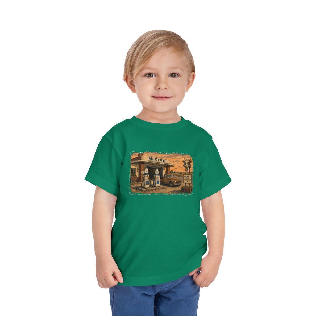 Toddler wearing the Peculiar Gas Station Toddler Tee in Kelly, gas station scene on the front