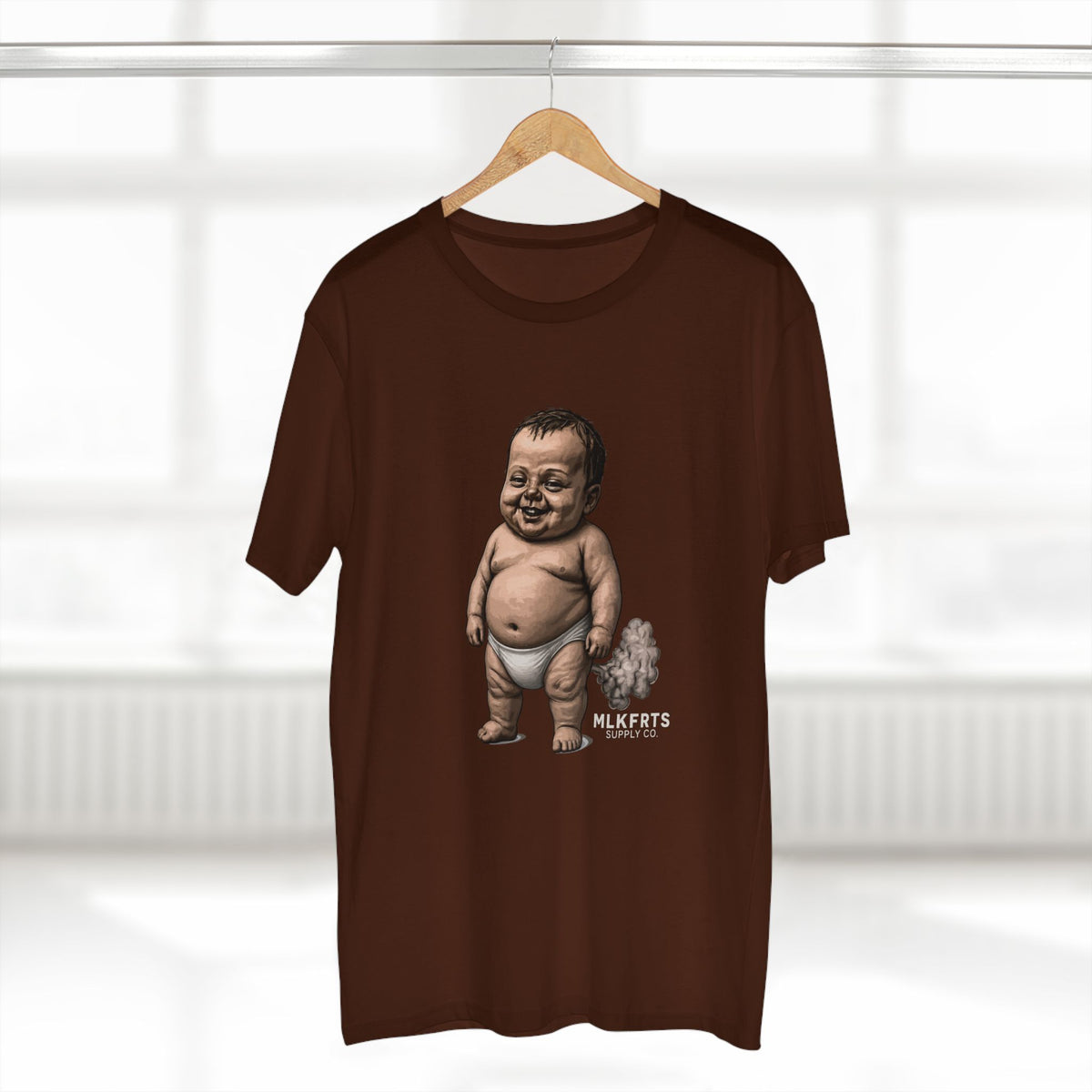 Dark chocolate MLKFRTS Lil' Stinker Tee on a hanger, smug diaper baby with gas cloud and milk puddles on the front