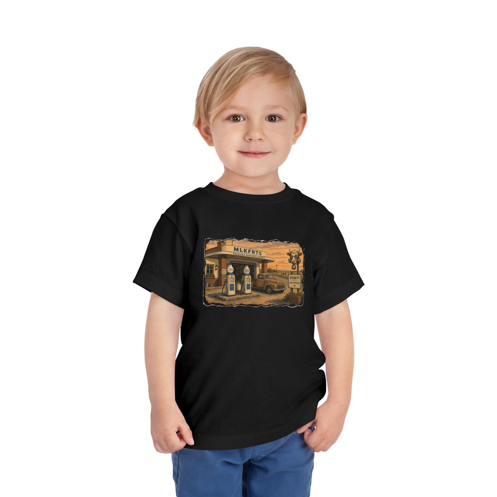 Toddler wearing the Peculiar Gas Station Toddler Tee in Black, gas station scene on the front