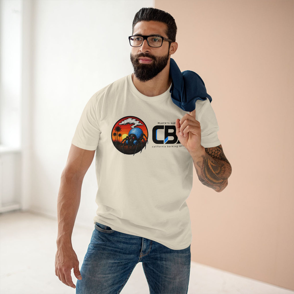 Man wearing the MLKFRTS California Barking Spiders Tee in natural, front: CBS lockup with the gas-masked spider