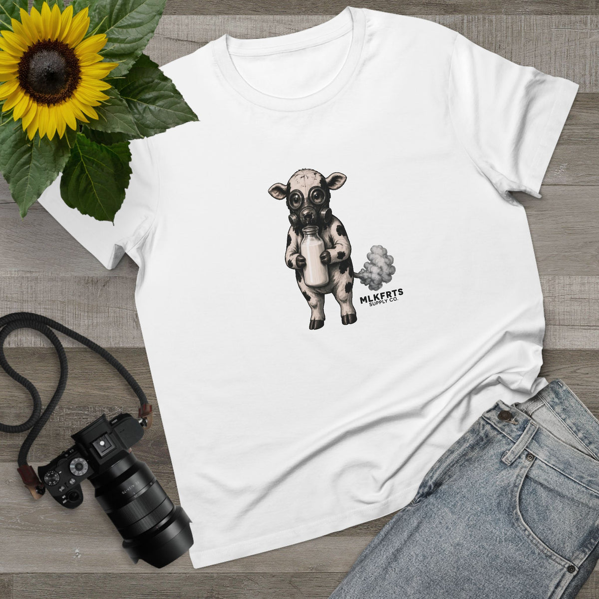 White women's tee with the Calf of Concern on the front, flat lay with a sunflower, camera and jeans