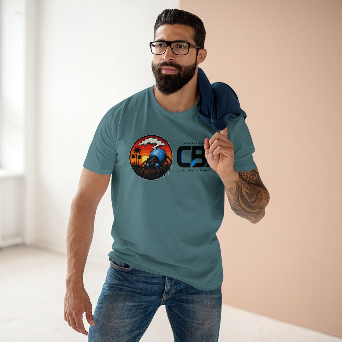 Man wearing the MLKFRTS California Barking Spiders Tee in slate blue, front: CBS lockup with the gas-masked spider