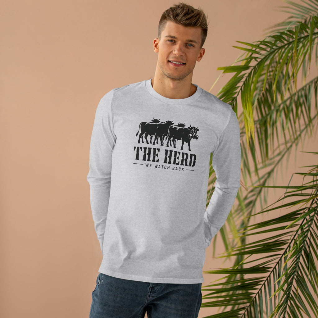 Man wearing the Watch Back Long Sleeve Tee in light grey, front: cow lineup with one gas-mask cow, THE HERD, We Watch Back