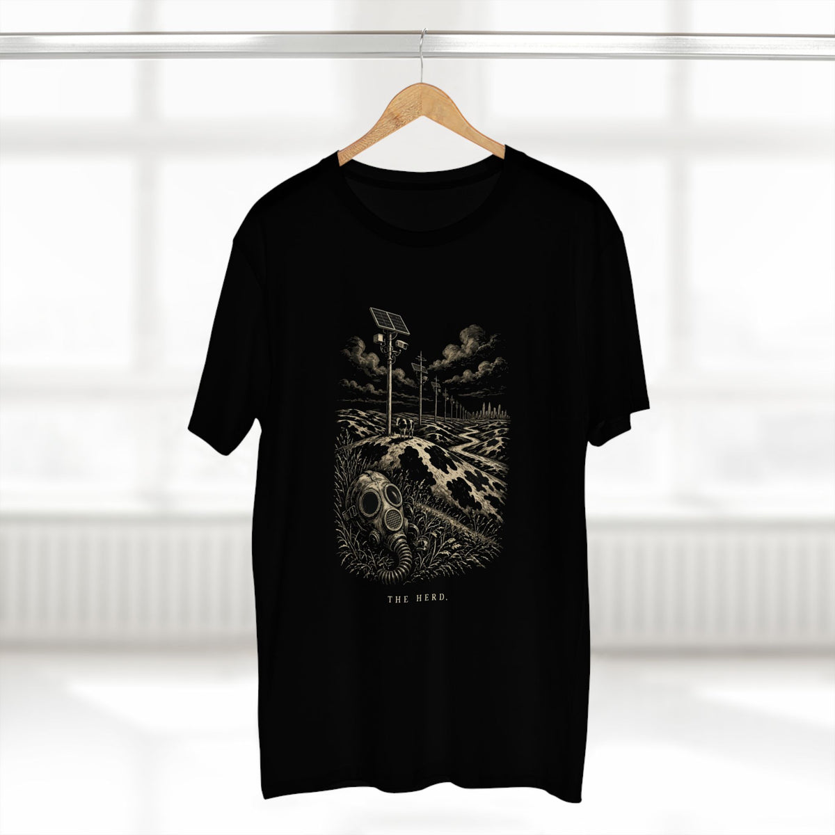 The Hills Have Cams Tee in black on a hanger, front: etched surveillance hills with a gas mask in the grass, THE HERD.