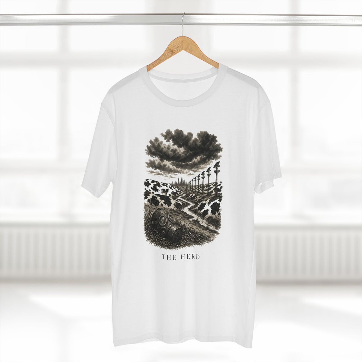 The Hills Have Cams Tee in white on a hanger, front: etched surveillance hills with a gas mask in the grass, THE HERD.
