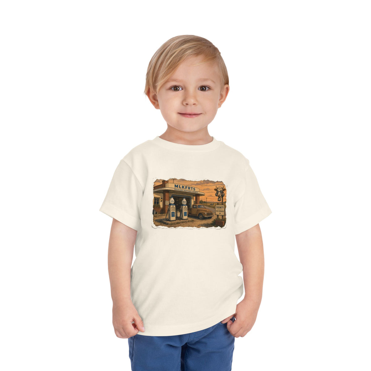 Toddler wearing the Peculiar Gas Station Toddler Tee in Natural, gas station scene on the front