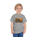 Toddler wearing the Peculiar Gas Station Toddler Tee in Athletic Heather, gas station scene on the front
